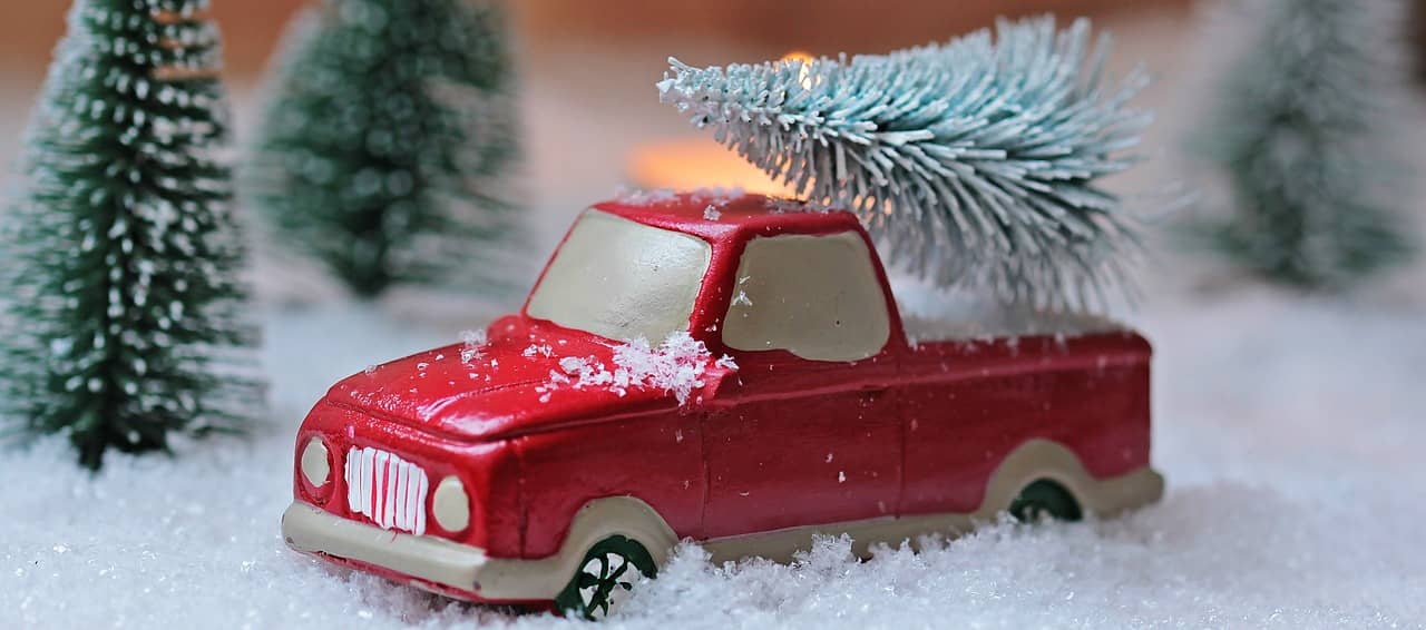 Zabawkowy samochód z choinką na pace w zimowej scenerii